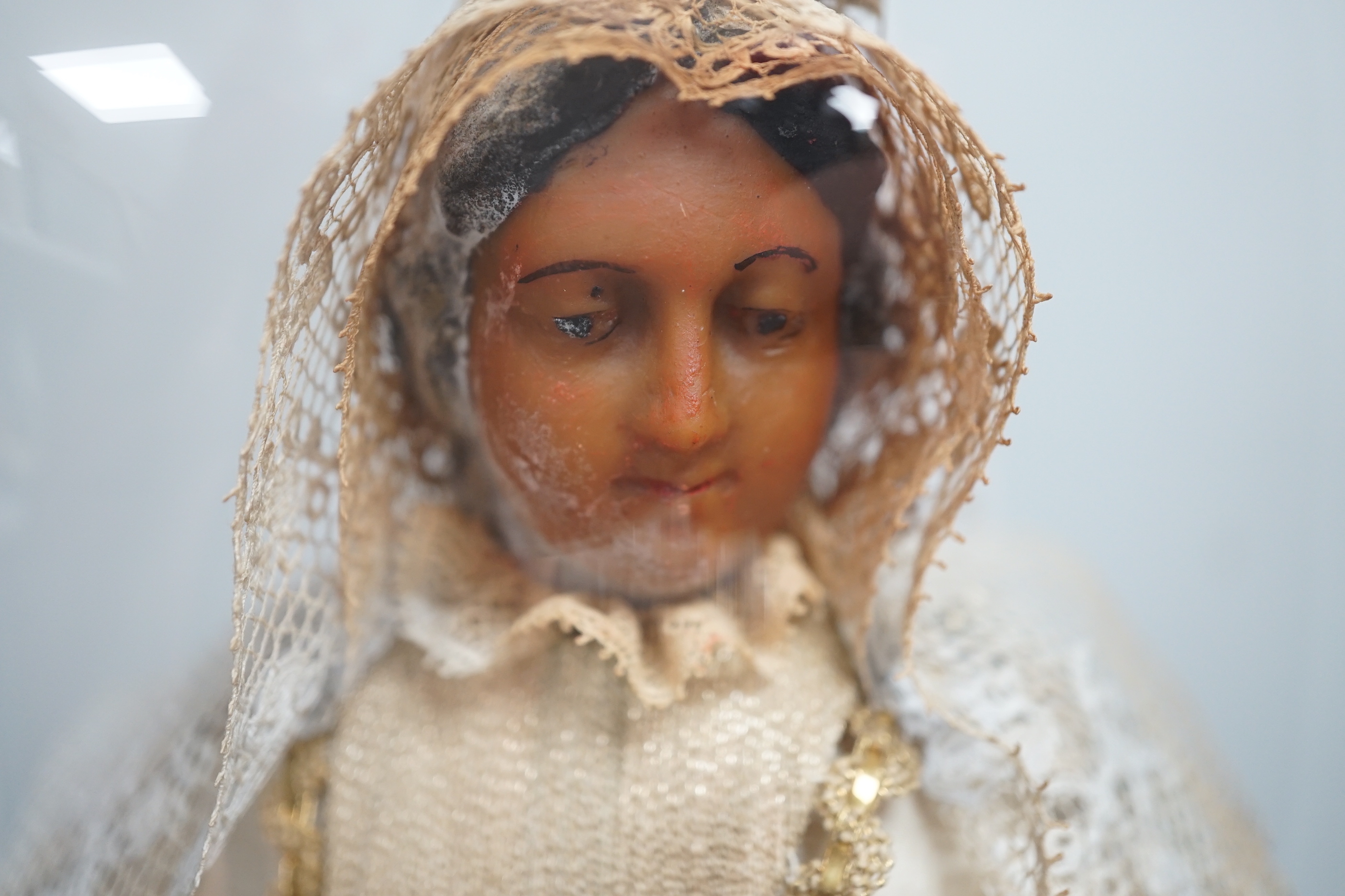 A waxed dressed figure with crown holding a baby under a glass dome 49.5cm high